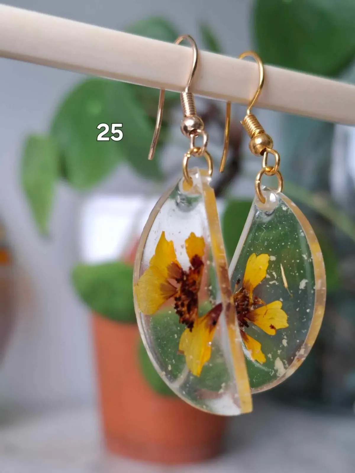 Boucles d'oreilles pendantes en résine transparente renfermant de petites fleurs jaunes séchées.