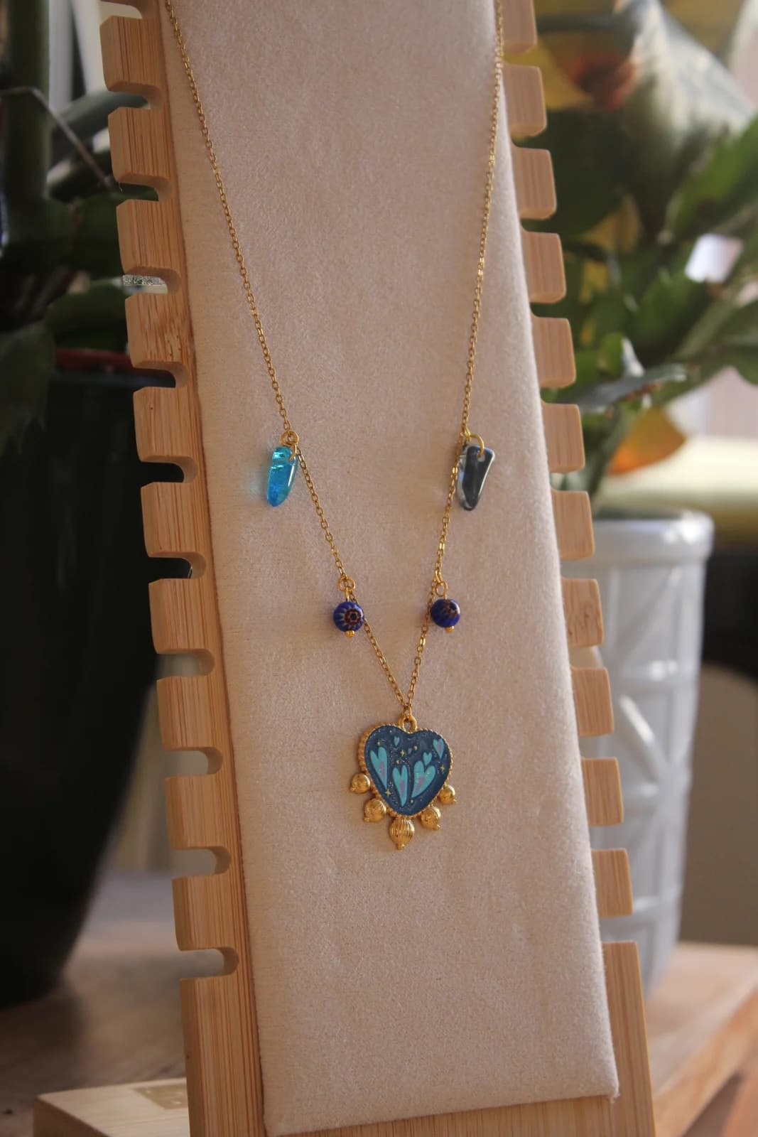 Collier doré en acier inoxydable avec pendentif cœur bleu et pampilles bleues sur présentoir en bois