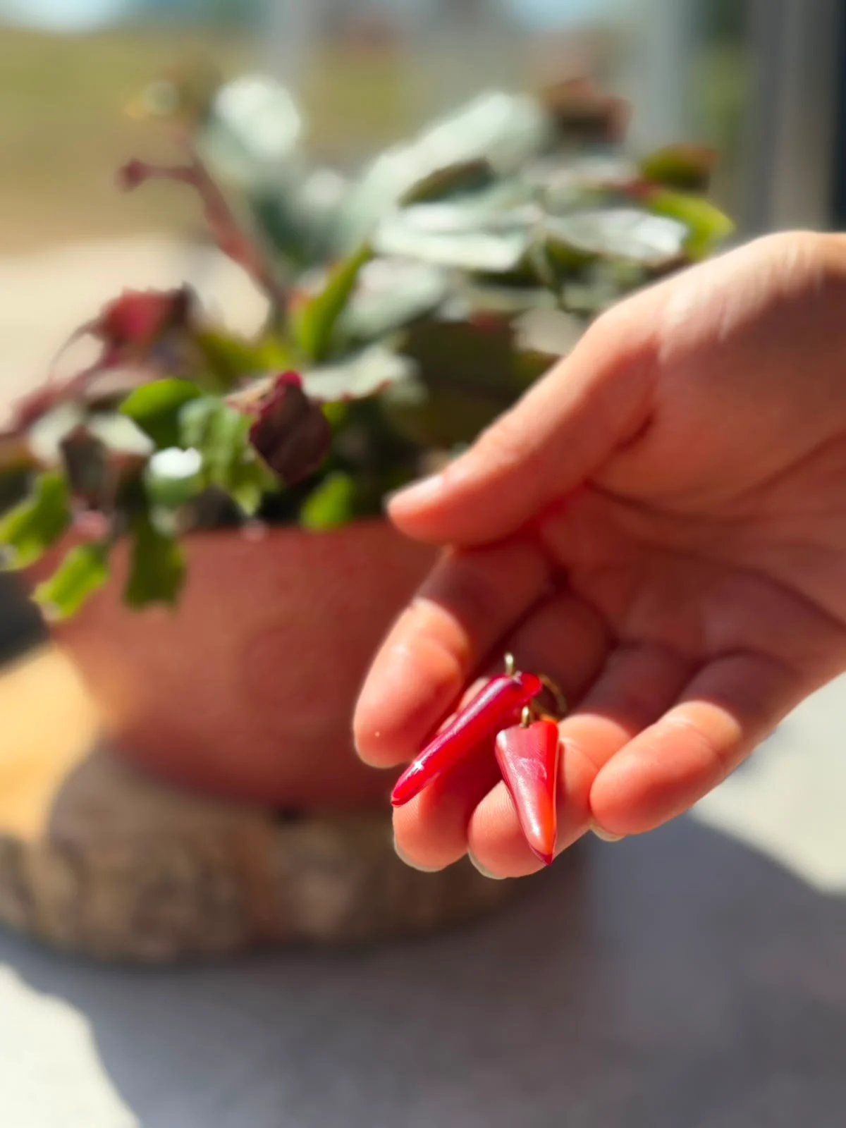 Boucles d'oreilles pendantes en verre rouge tenues au creux d'une main.