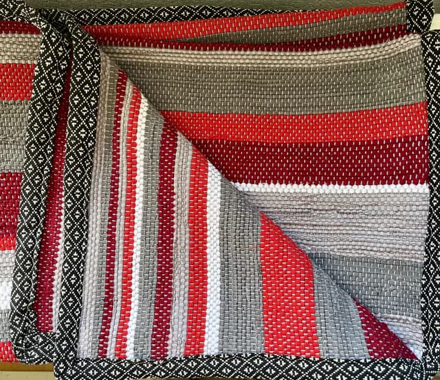 Plaid tissé à rayures rouges, bordeaux et grises avec bordure à motifs géométriques