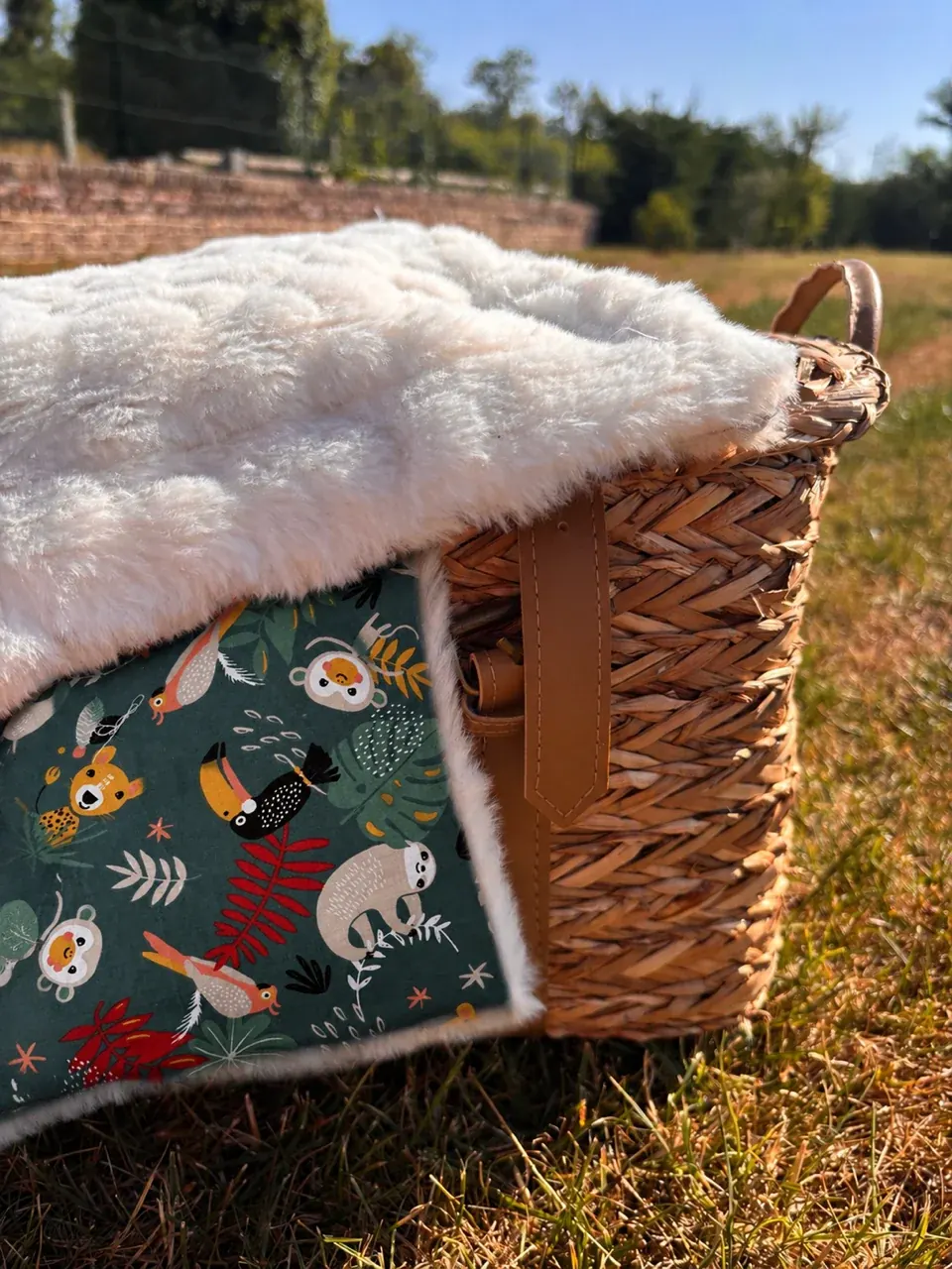 Couverture bébé motif jungle avec toucan et paresseux suspendue au lit à barreaux.