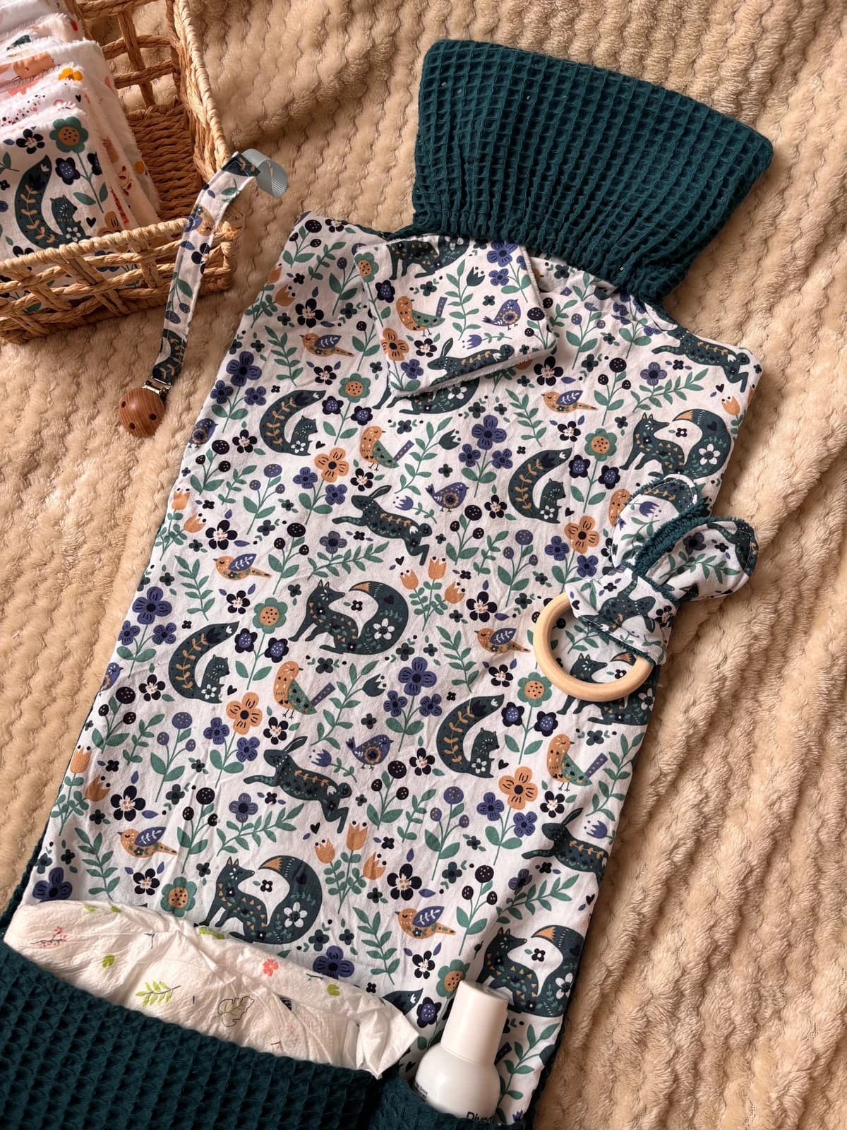 Tapis à langer déplié motif animaux de la forêt et tissu nid d'abeille vert foncé avec accessoires assortis.