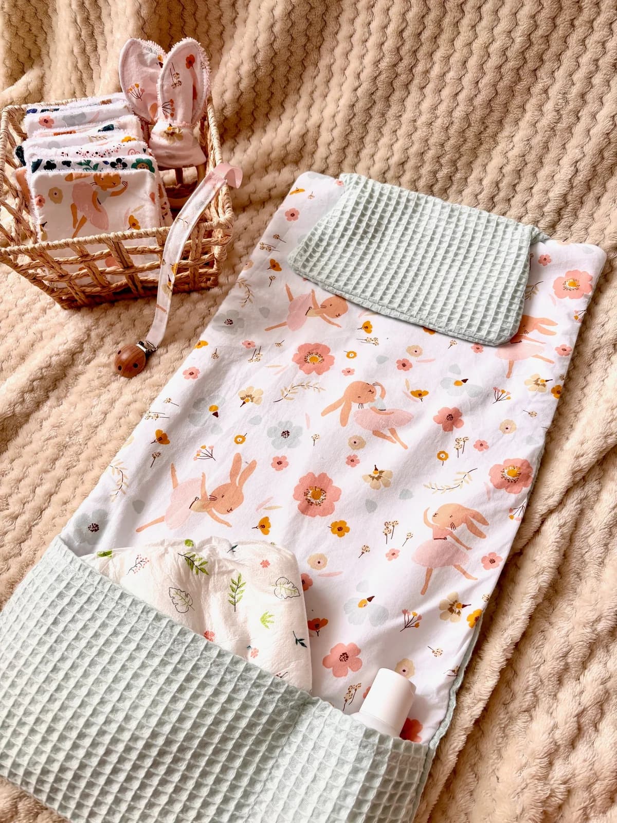 Tapis à langer nomade déplié à motifs de lapins et fleurs, avec poches vert d'eau.