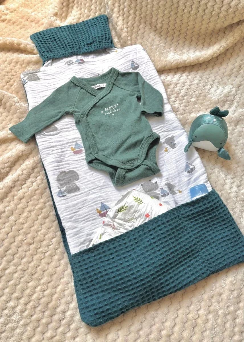 Tapis à langer nomade déplié à motifs illustrés et tissu nid d'abeille bleu, avec body bébé et doudou