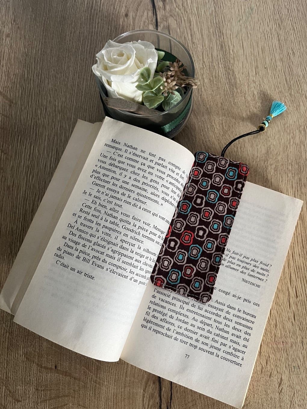 Marque-page en tissu à motifs géométriques rétro posé sur les pages d'un livre ouvert.