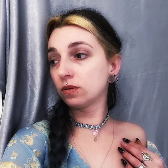 Ras de cou tissé bleu et doré orné d'un pendentif irisé et d'une perle grise porté au cou
