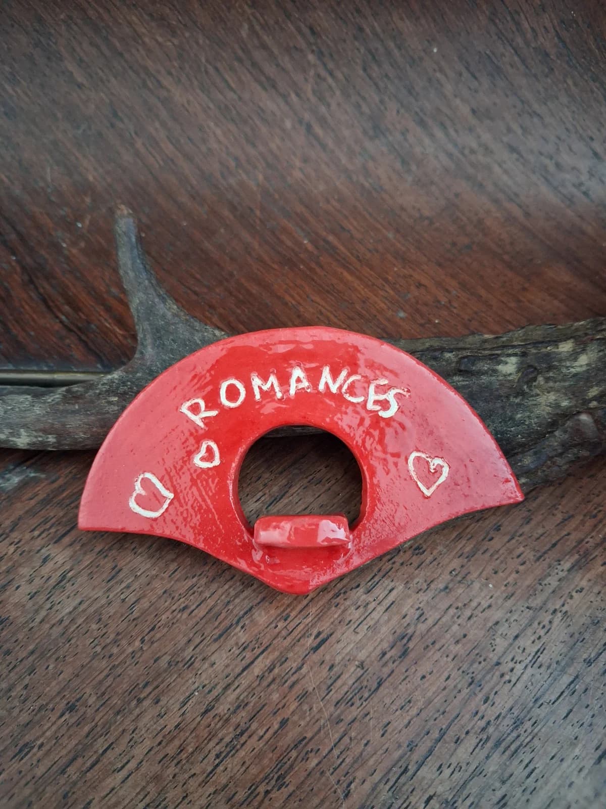 Porte-page en céramique rouge vif orné de l'inscription Romances et de petits cœurs blancs.