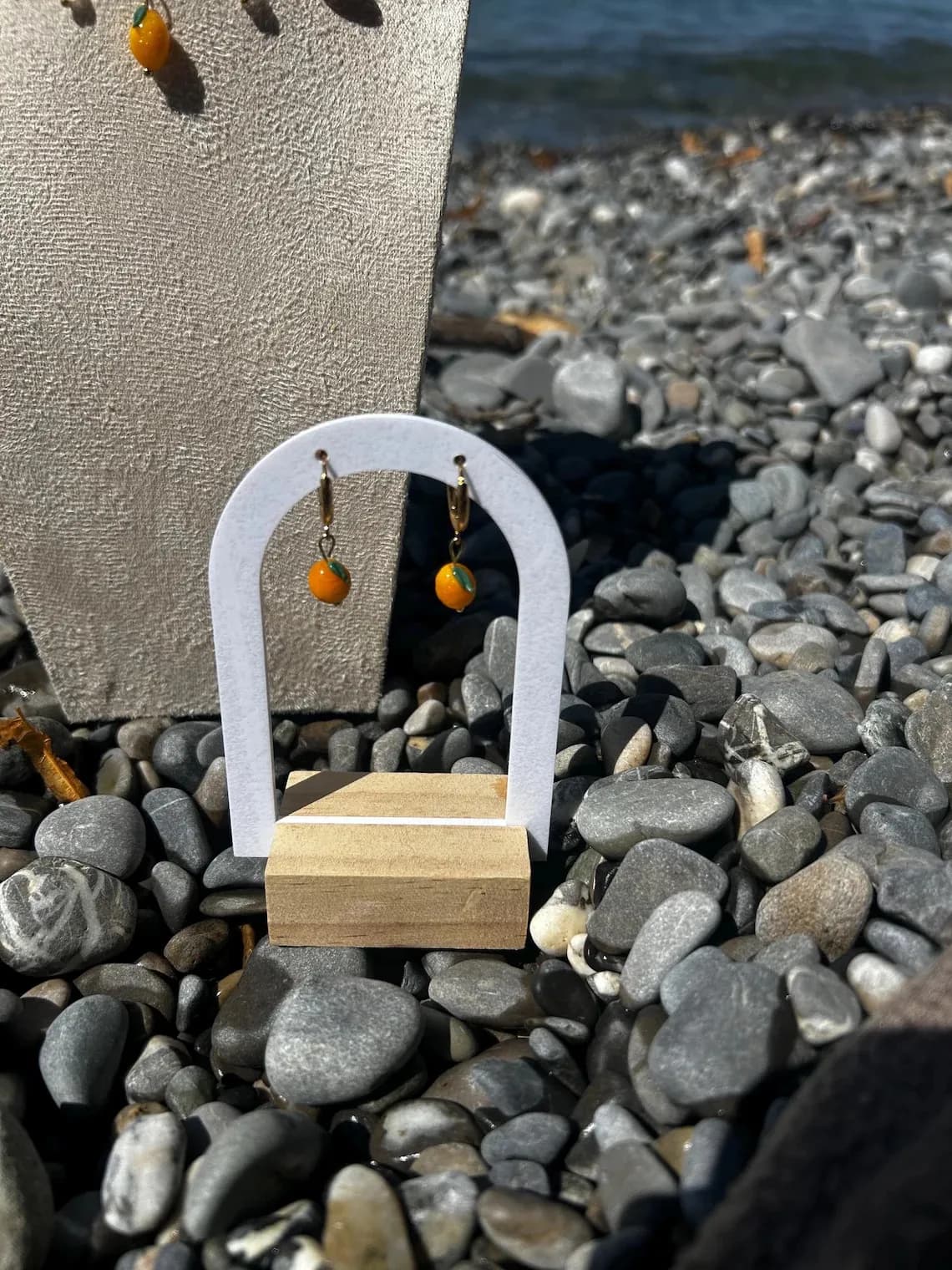 Boucle d'oreille citron jaune portée à l'oreille par une femme avec un collier à pendentifs assortis.