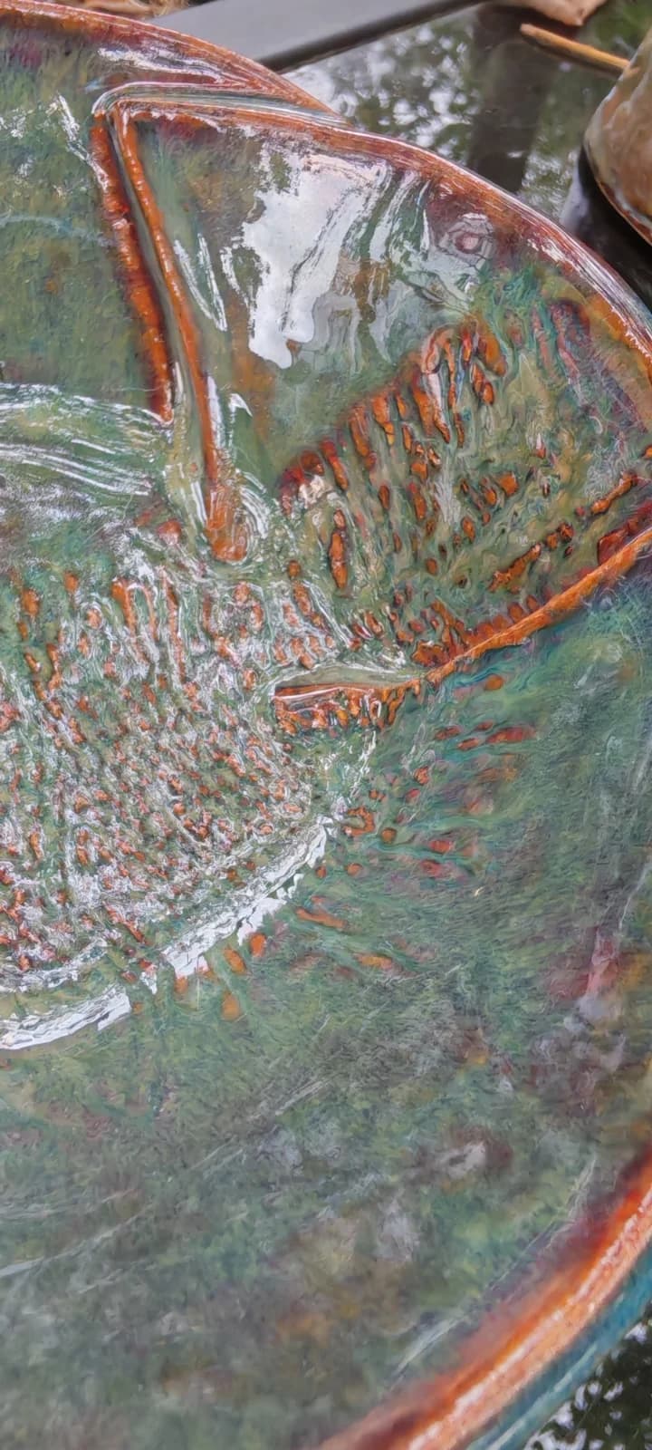 Gros plan sur l'émail vert brillant et les textures cuivrées d'inspiration végétale de la coupelle.