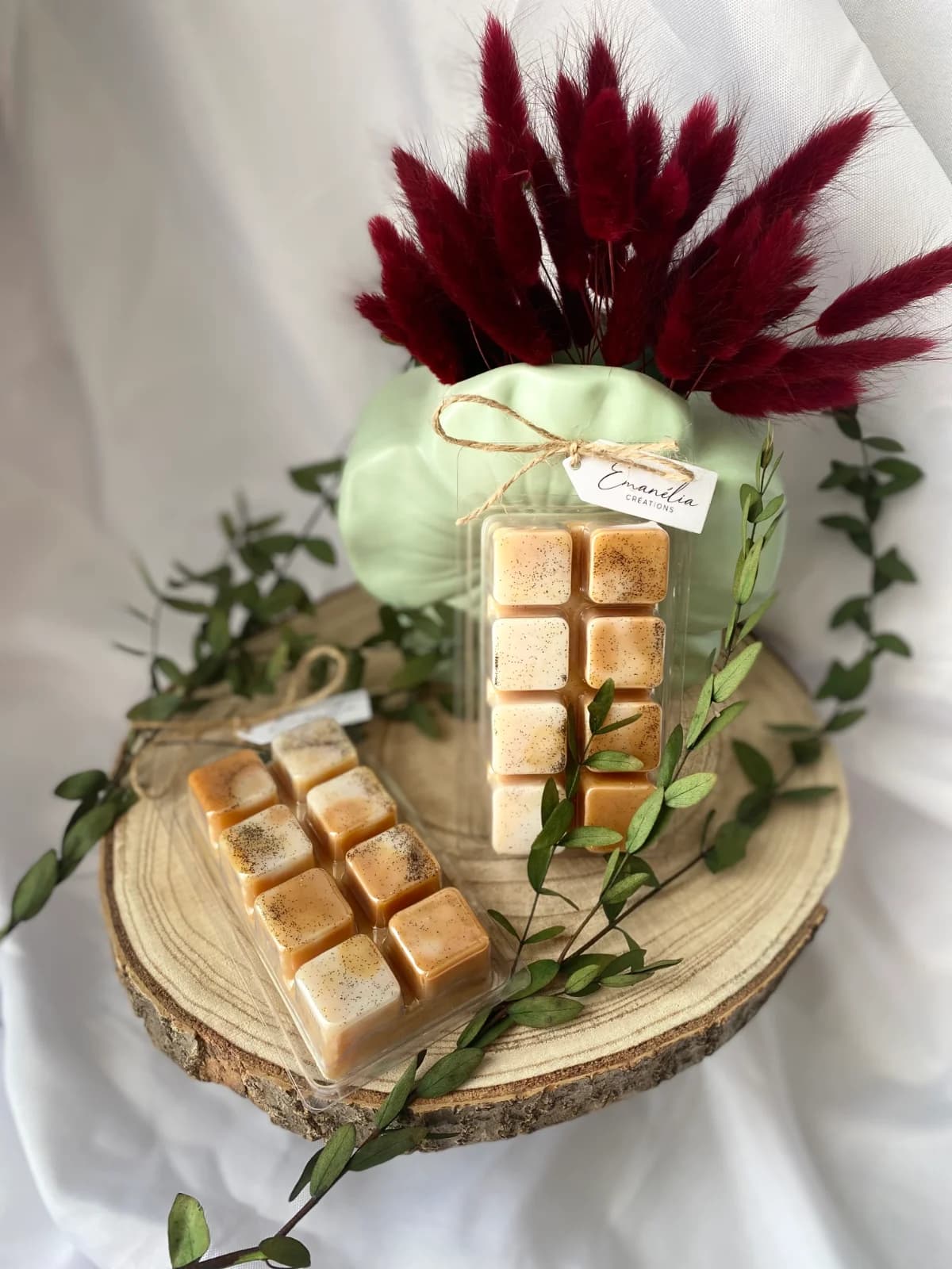 Deux tablettes de cire parfumée à huit carrés mouchetés présentées sur une tranche de bois.